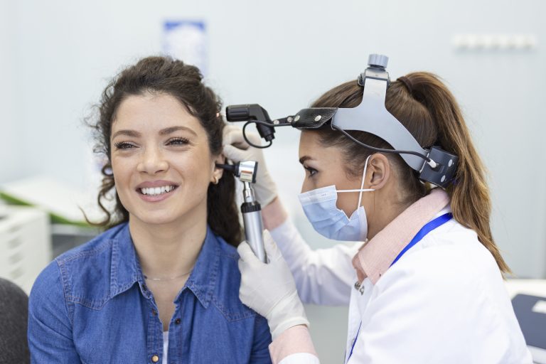 Hearing exam. Otolaryngologist doctor checking woman's ear using otoscope or auriscope at medical clinic